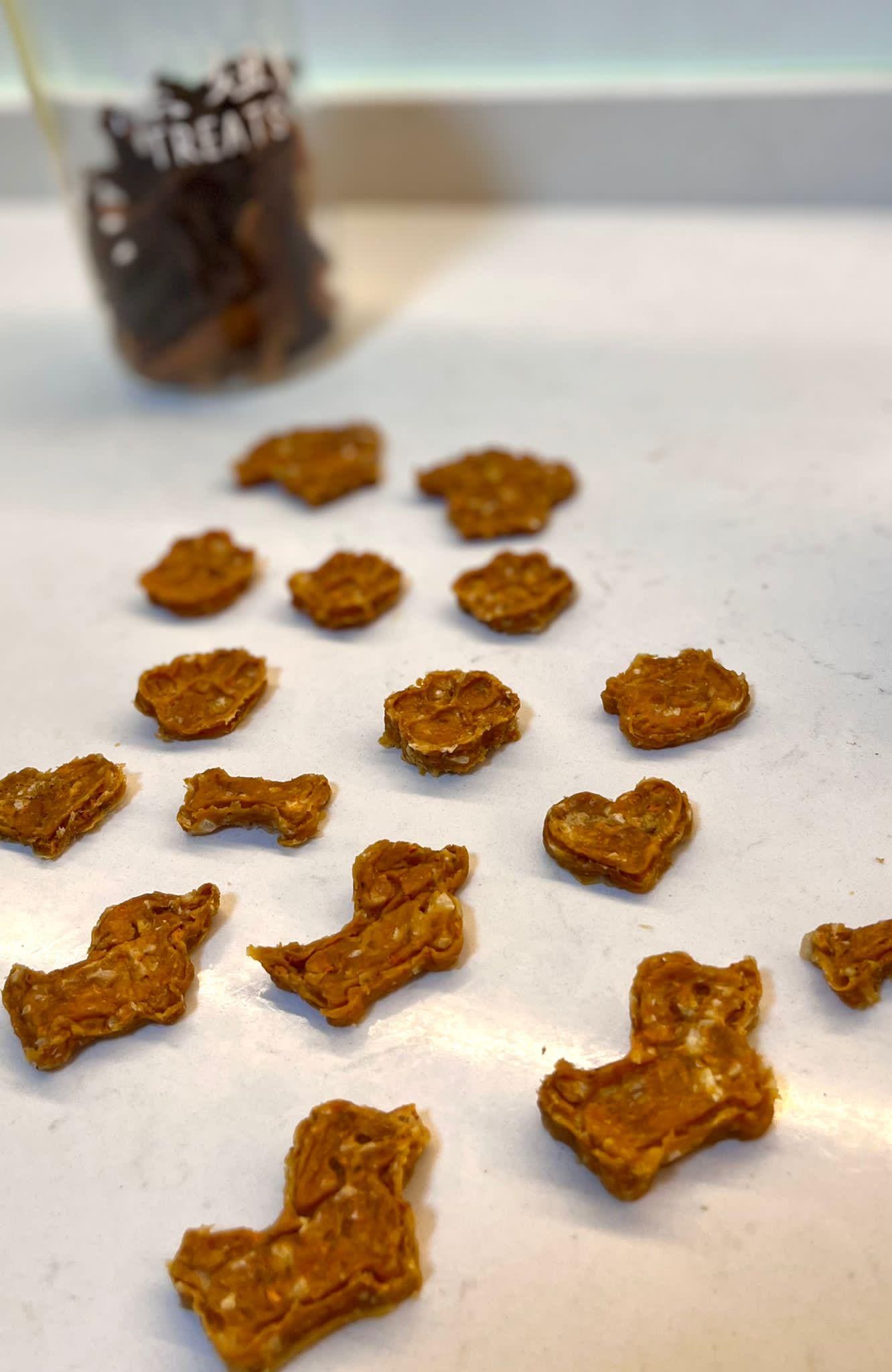 Cookies scattered on a white counter with a TREATS jar behind